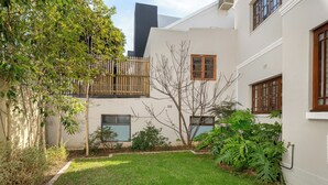 Une cour avec une pelouse verdoyante, une clôture en bois et diverses plantes.