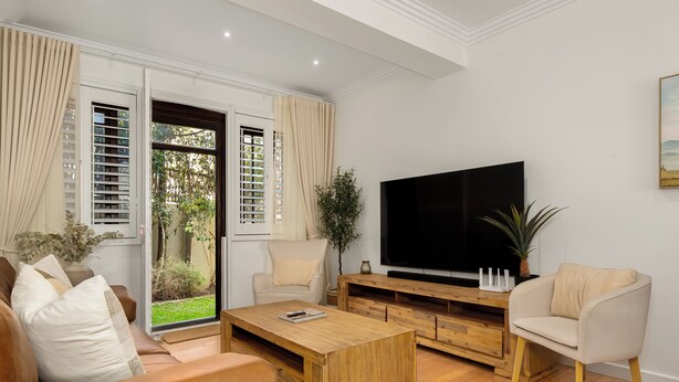 Un salon moderne comprenant un canapé, une table basse, un téléviseur et un meuble de rangement en bois.