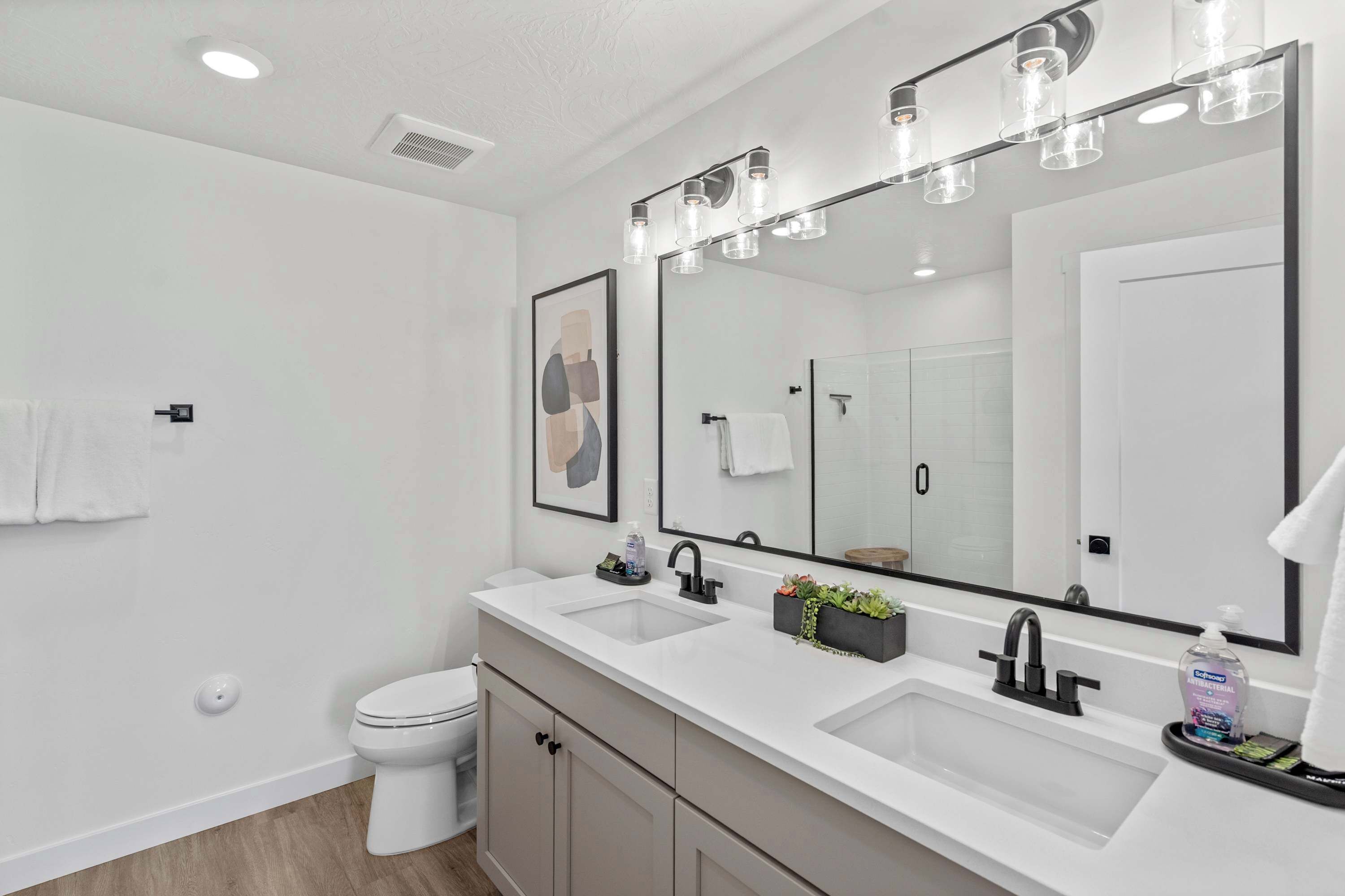 Un baño moderno con un lavamanos blanco, un espejo grande y un inodoro.