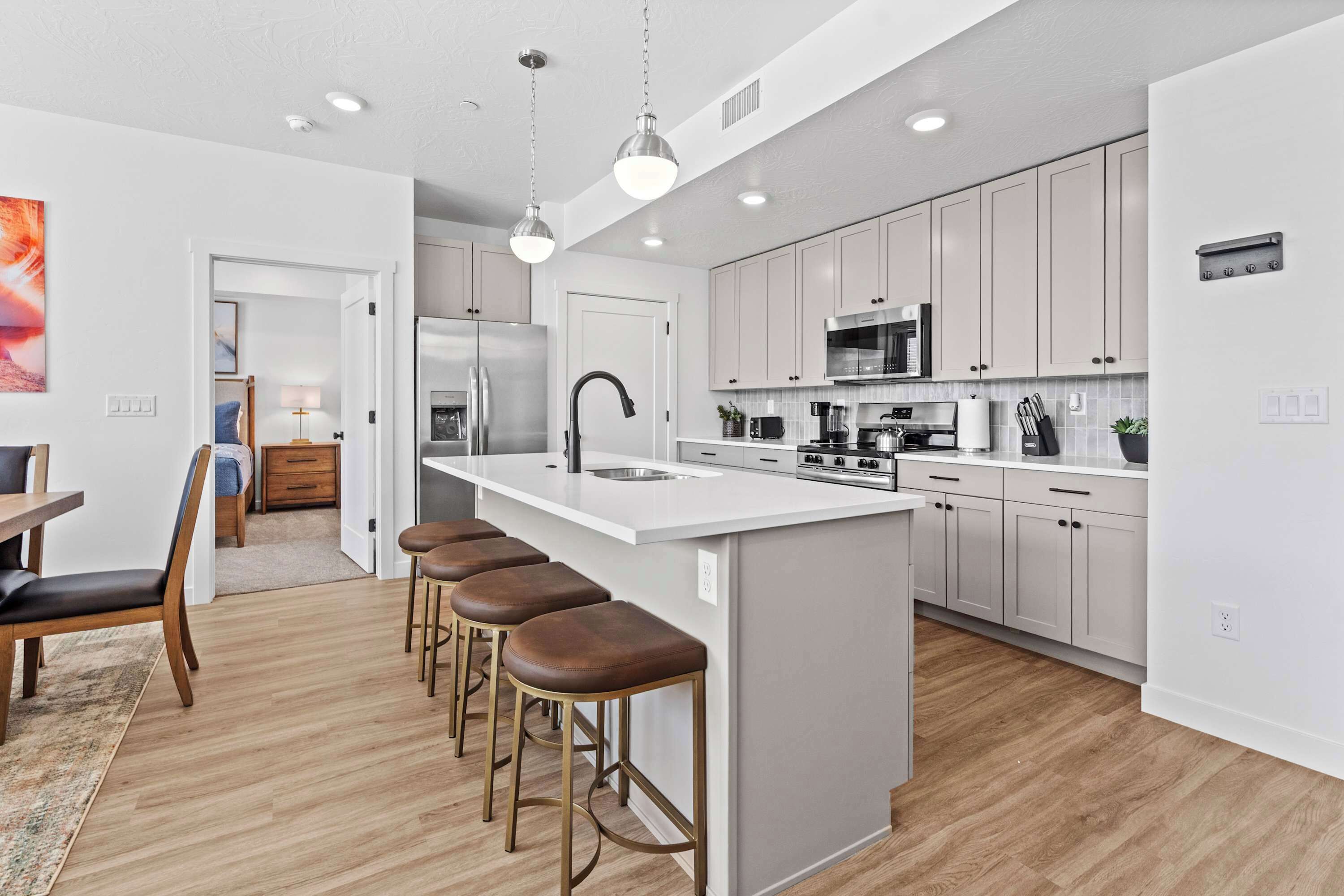 Una cocina moderna con una isla central, taburetes de bar y una zona de comedor con mesa y sillas.