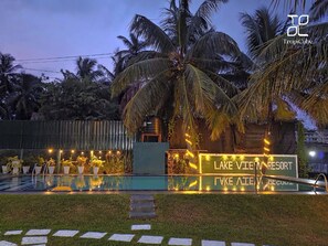 Un resort con piscina, palmeras y un cartel que dice 'Lake Vlee Resort'.
