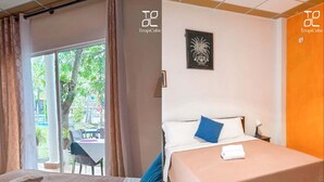 Habitación de hotel con una cama, una ventana con cortinas y vistas al exterior, además de una pared decorada con un cuadro.
