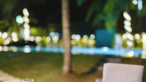 An outdoor dining setup with a white tablecloth, two plates of food, and two glasses of water. - Lake View Resort (Pamunugama)