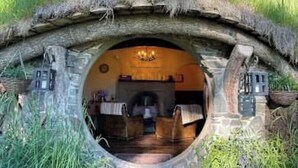 A rustic stone tunnel entrance leading to a cozy interior with a fireplace and wooden furniture.