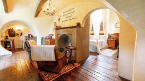 A cozy room with a fireplace, a comfortable armchair, and a rustic wooden floor.