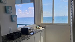 A kitchen with a view of the ocean, a toaster, and a basket on the counter.