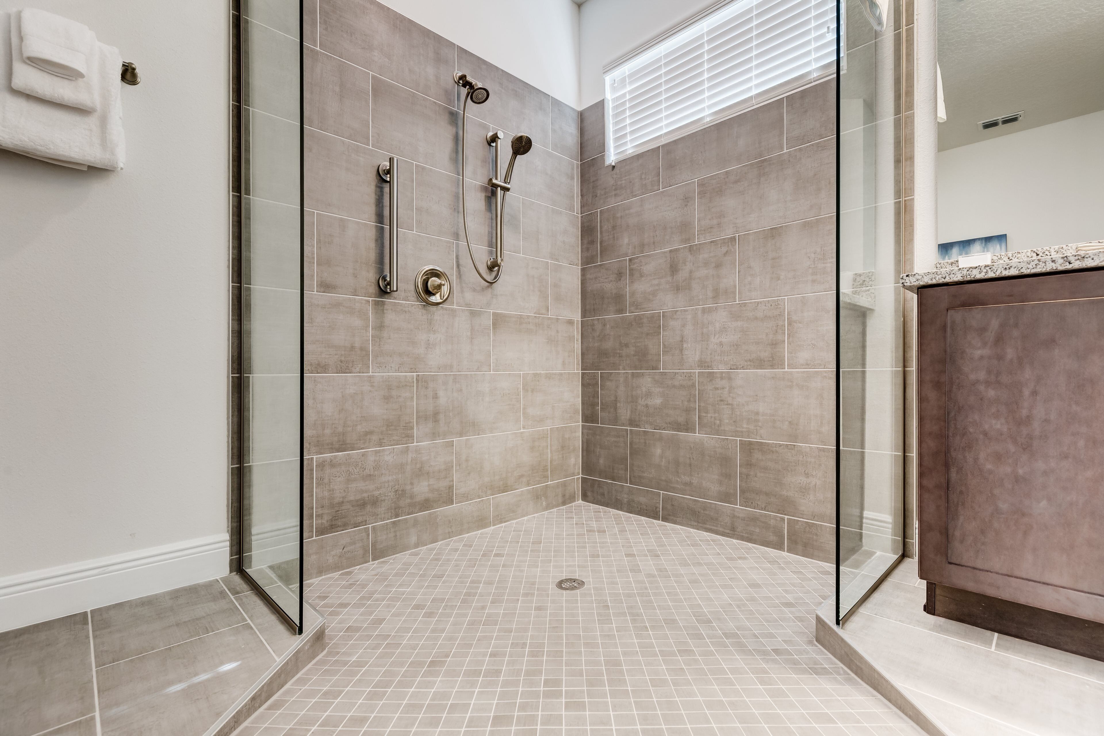 A walk-in shower with a glass door, tiled walls, and a marble floor.