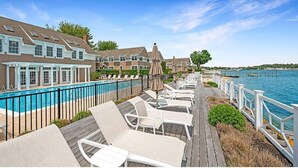 A poolside area with lounge chairs and umbrellas, a wooden deck, and a view of the water. - Heart of the Hamptons, Waterfront with Pool!  1 Bed/1 Bath Townhome (Hampton Bays)