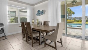 A dining area with a table and chairs, a ceiling fan, and a view of a swimming pool. - Last Minute Disney! Private Pool, Hot Tub, Game Room & Themed Bedrooms. Book Now! #37046 (Orlando)