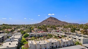Un quartier résidentiel avec des immeubles d’appartements, une montagne en arrière-plan et un ciel dégagé.