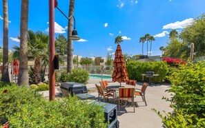 Ein Terrassenbereich im Freien mit Pool, Sitzgelegenheiten und einem großen Sonnenschirm.