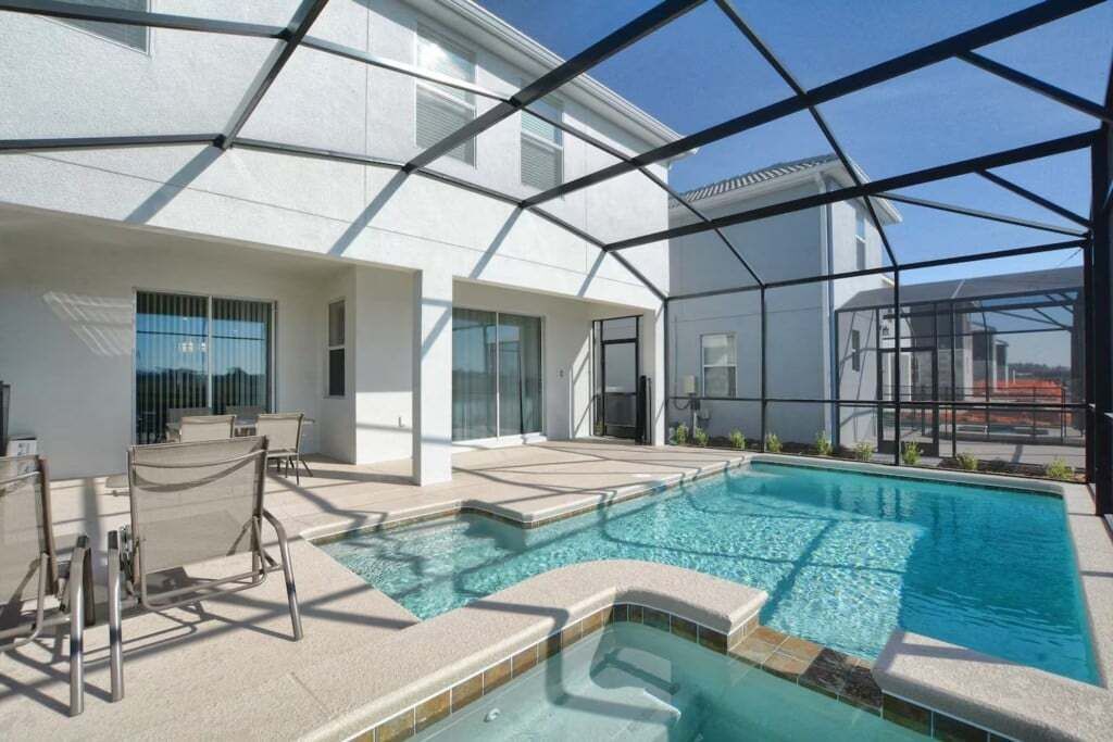 A modern indoor pool area with clear glass walls, a pool, and seating.