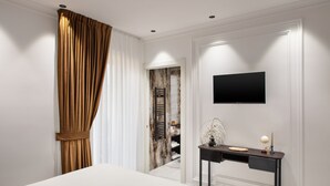 Een moderne hotelkamer met een groot bed, een bureau met een flatscreen televisie, en uitzicht op een hal met een houten deur.