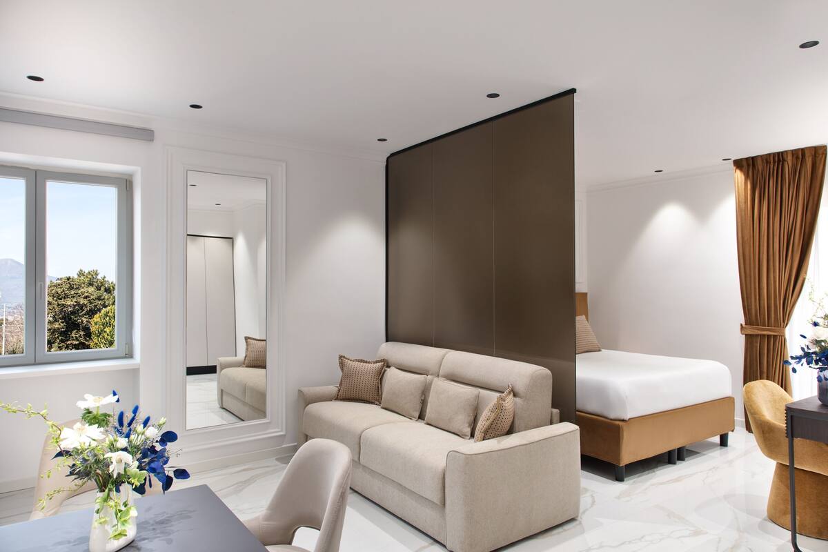 Une chambre d’hôtel moderne équipée d’un canapé, d’un lit, d’une table à manger et offrant une vue sur l’extérieur.