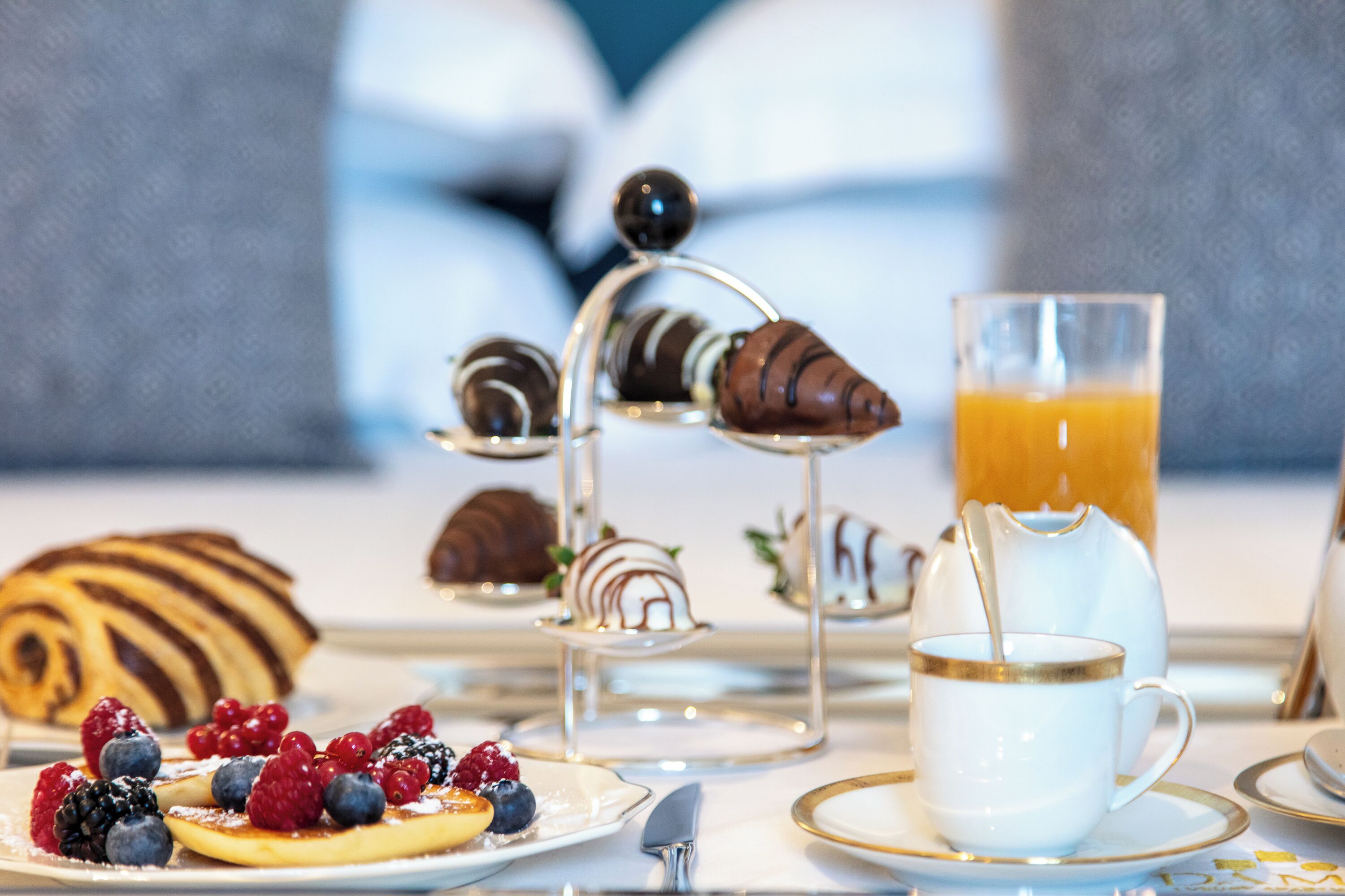 A breakfast setting with pastries, fruits, and a glass of orange juice.