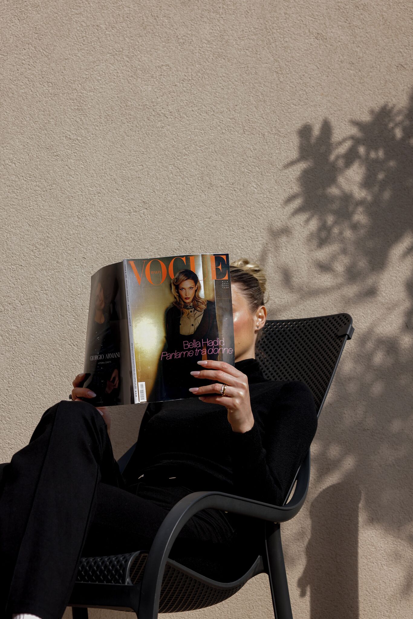 A person sitting on a chair with a magazine.