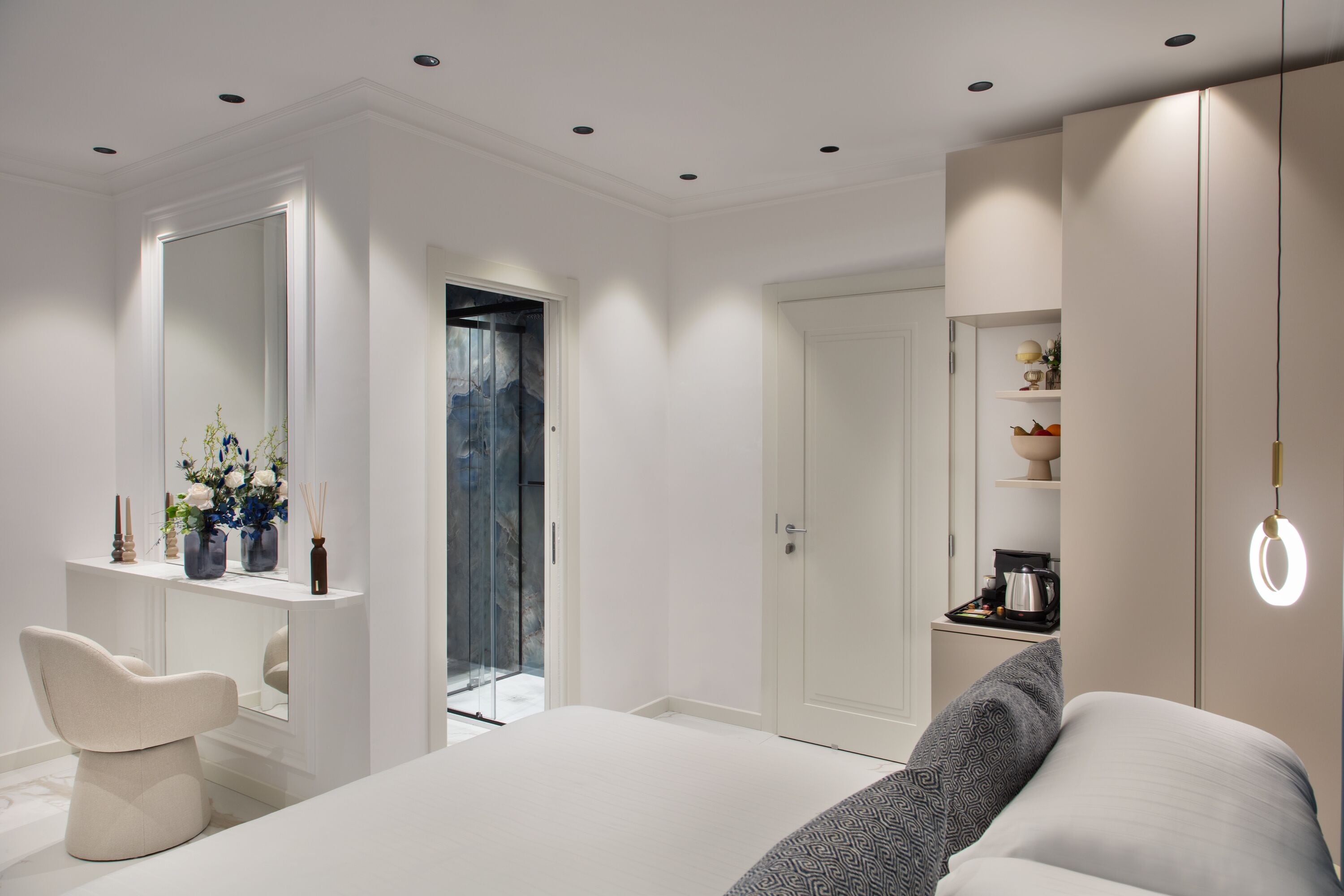 Une chambre à coucher moderne avec un grand lit, une coiffeuse avec un miroir et un dressing.