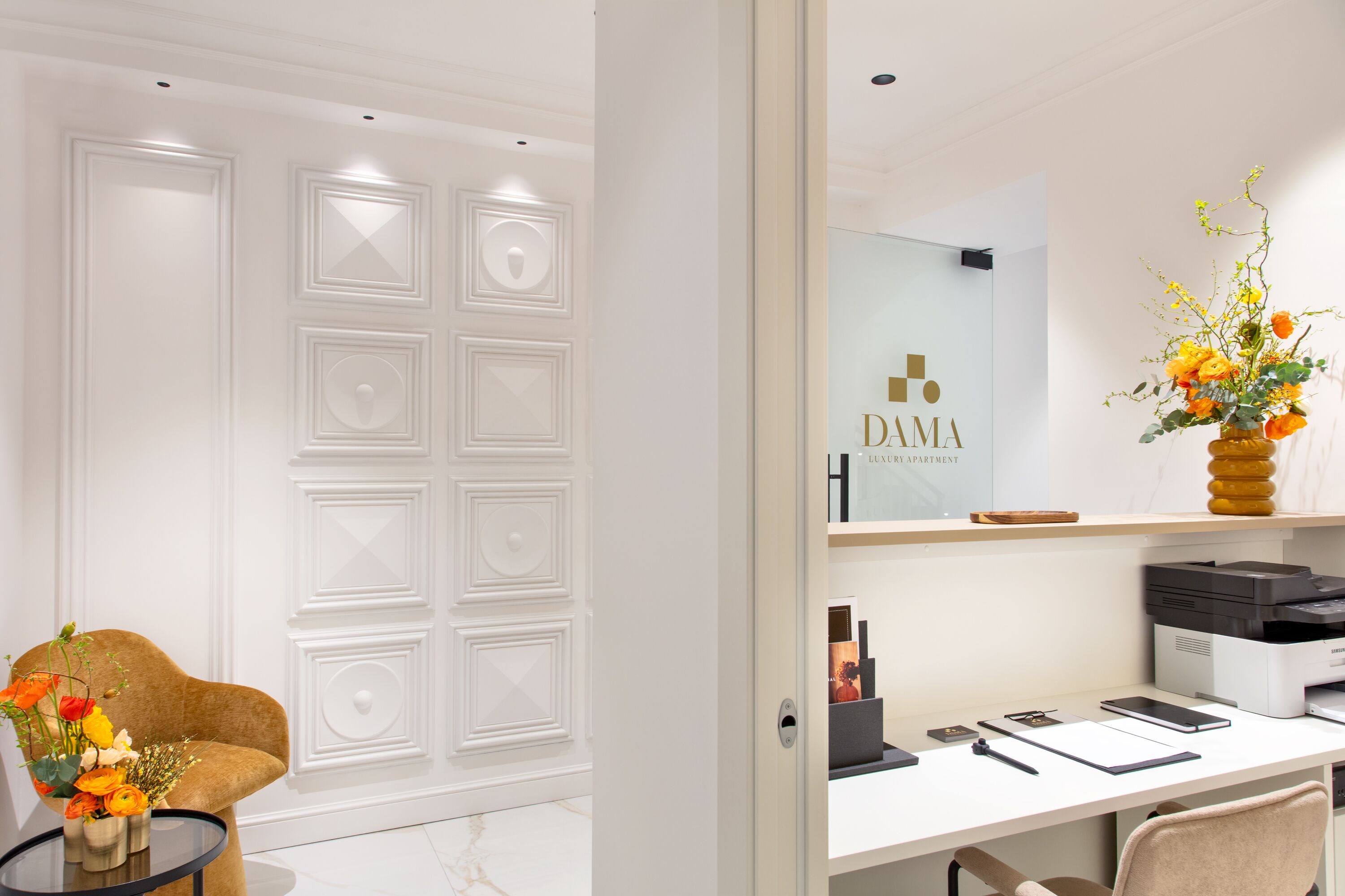 A modern office space with a desk, chair, and a vase of flowers.