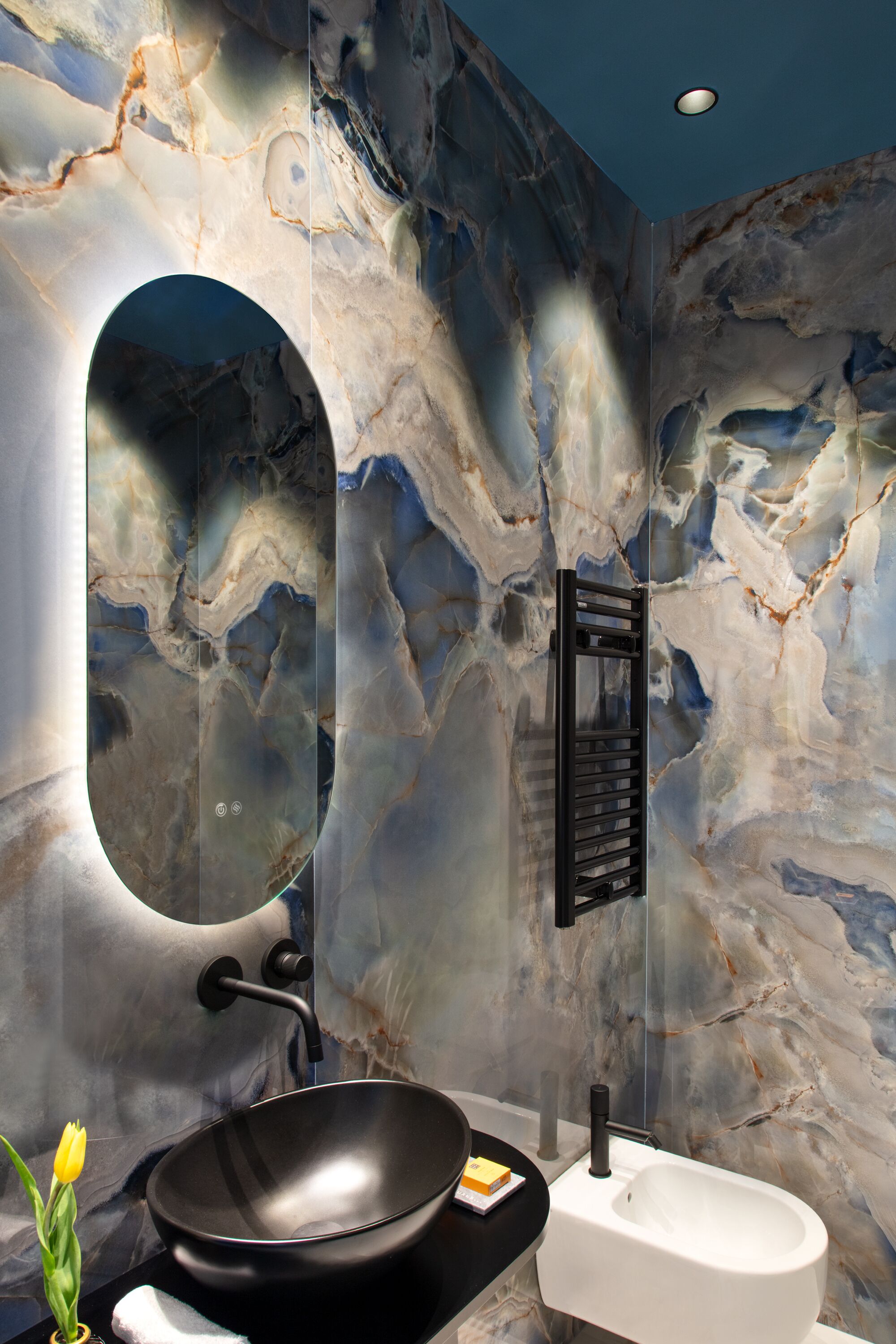 A bathroom with a black sink, white urinal, and a marble wall with a unique pattern.