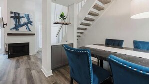 Ein moderner Essbereich mit einem langen Tisch, blauen Sitzmöbeln und einer Treppe mit Steinstufen.