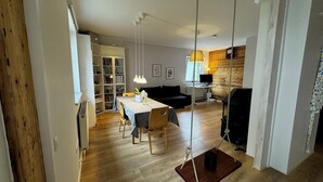 Un espacio de estar moderno con comedor, un sofá negro, una estantería de madera y una chimenea.