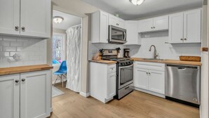Une cuisine moderne avec des armoires blanches, des appareils en acier inoxydable et un plan de travail en bois.
