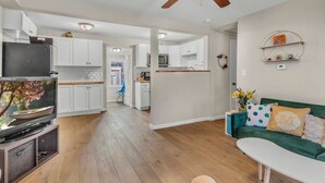 Un salon moderne avec un téléviseur, un canapé vert et une table basse blanche.