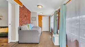 Un salon chaleureux avec un canapé gris, un mur en briques et un plafond en bois.