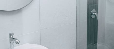 A modern bathroom with a round mirror, a sink, and a toilet.