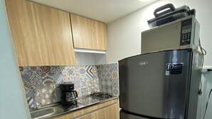 Une cuisine compacte avec des meubles en bois, une cuisinière à gaz, une machine à café et un réfrigérateur en acier inoxydable.