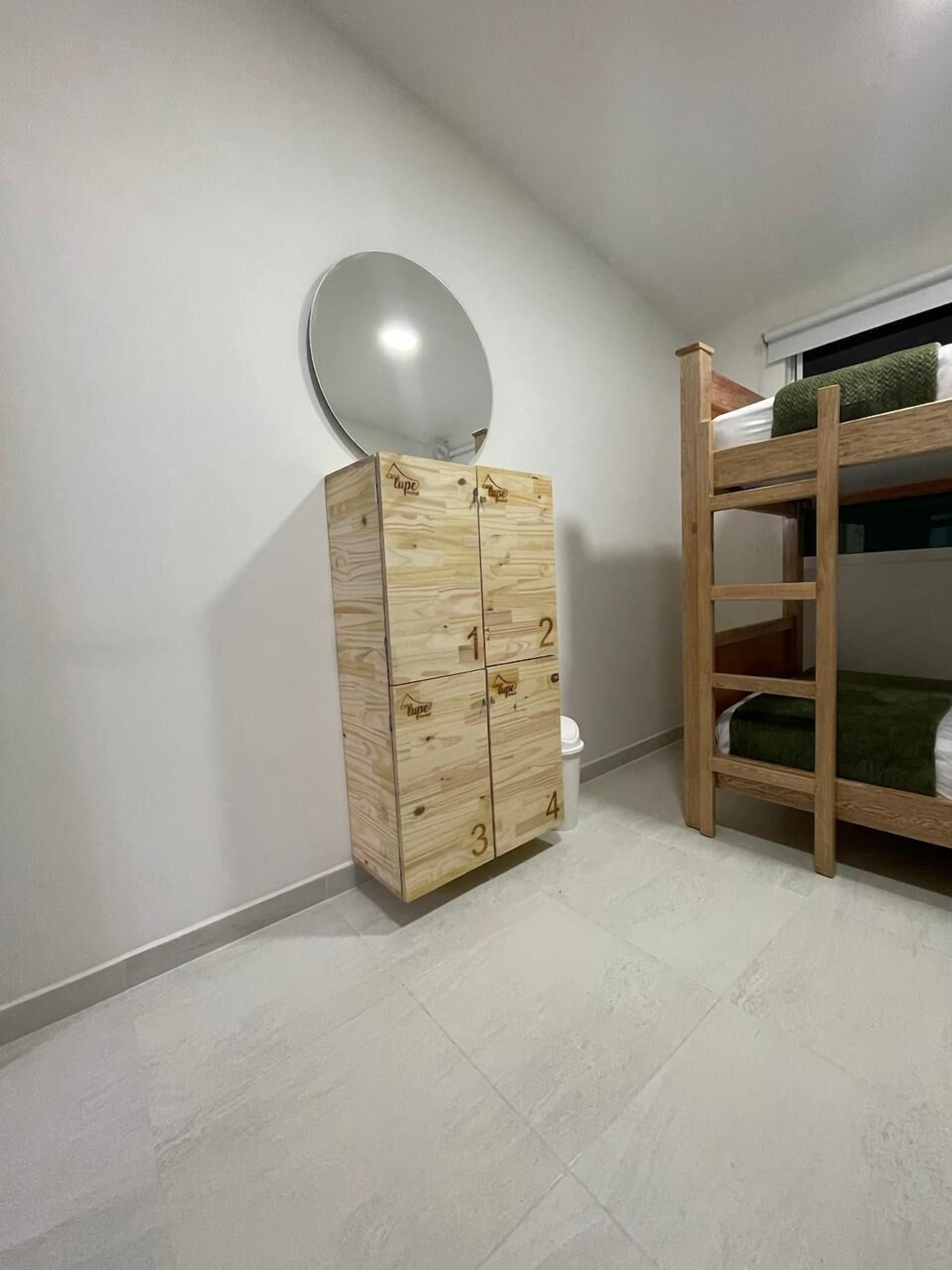Une pièce avec un meuble en bois doté de tiroirs, un lit superposé et un sol carrelé de carreaux blancs.