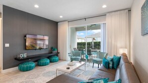 A modern living room with a flat-screen TV, a sofa, a coffee table, and a dining area with chairs. - Last Minute Disney! Private Pool, Hot Tub & Themed Bedrooms. Book Now! #105343 (Orlando)