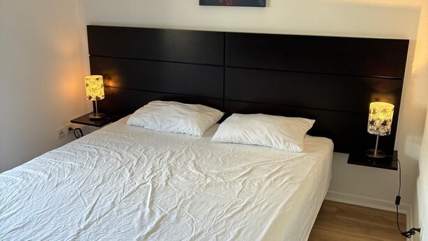 A neatly made bed with white linens, a dark headboard, and two bedside lamps with patterned shades. - 302, LE VIRGINIA, near the center of Grasse (Grasse)