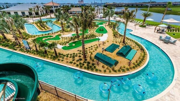 A pool area with multiple swimming pools, a water slide, and a golf course.