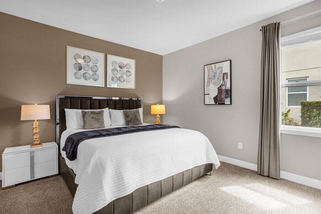 A bedroom with a bed, two bedside tables, and wall art.
