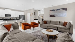 A modern living room with a grey sofa, orange armchairs, and a coffee table. - Last Minute Disney! Private Pool, Hot Tub & Themed Bedrooms. Book Now! #91365 (Orlando)