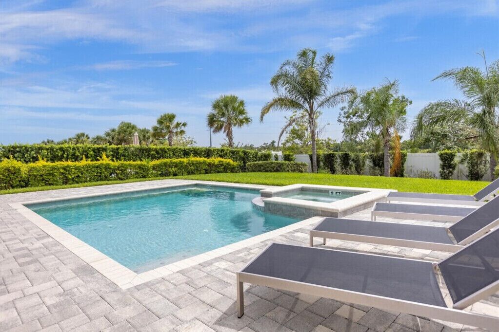 Ein Swimmingpool mit Liegestühlen und Palmen.