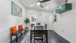 A dining area with a table, chairs, a bench, a ceiling fan, a clock, and a green cabinet.