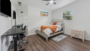 A bedroom with a bed, desk, chair, nightstand, and a ceiling fan.