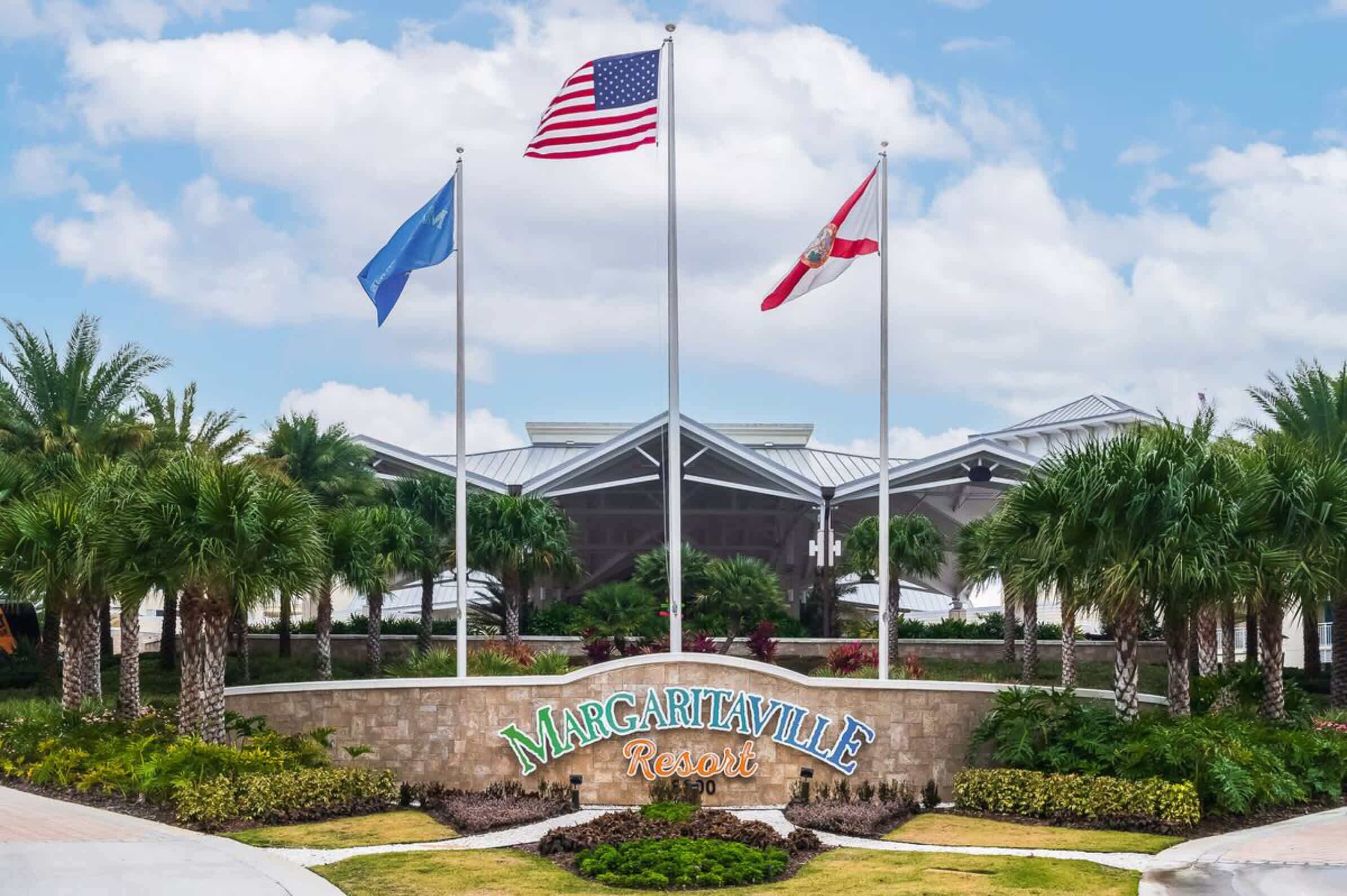 The entrance to Margaritaville Resort with a clear view of the building, palm trees, and flags.