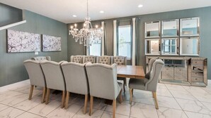 A dining area with a large table and chairs, a chandelier, and artwork on the walls.