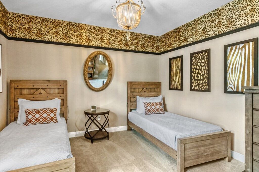 A bedroom with two wooden beds, a round mirror, and leopard print wallpaper.