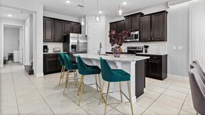 A modern kitchen with dark cabinets, a central island, and bar stools.