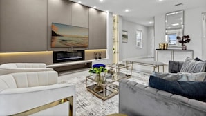 A modern living room with a large flat-screen TV, comfortable seating, and a decorative plant.