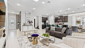 A modern living room with a sofa, coffee table, and a dining area with chairs.