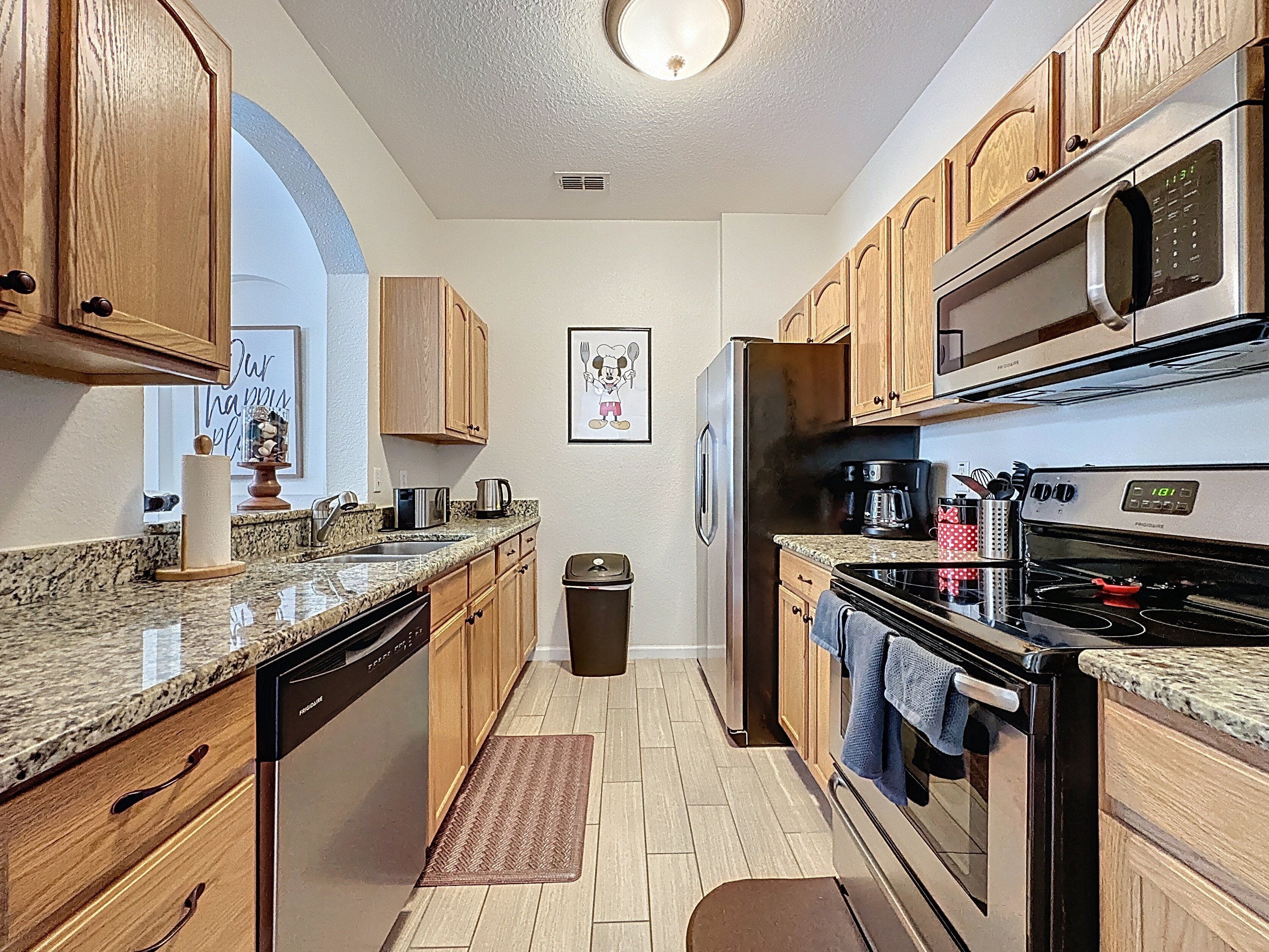 A kitchen with wooden cabinets, a stainless steel refrigerator, a microwave, and a stove.