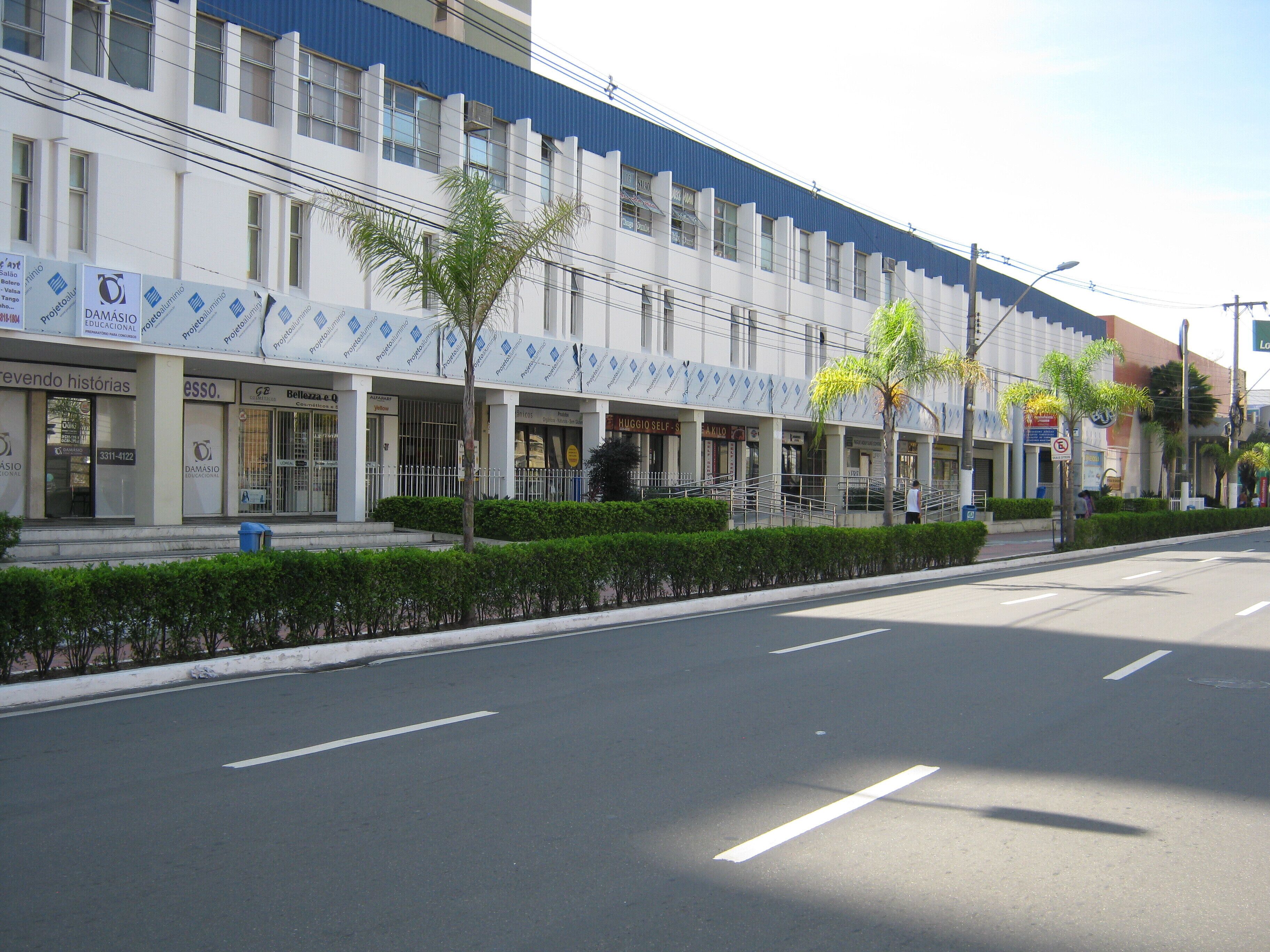 A multi-story building with commercial establishments on the ground floor, including a self-service store and a café.