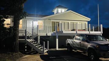 A two-story house with a balcony, a staircase, and a truck parked in front.