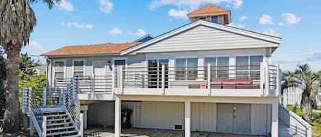 A two-story house with a covered porch, a staircase, and a small deck area.