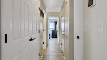 A hallway with white doors, a wooden floor, and a ceiling light fixture.